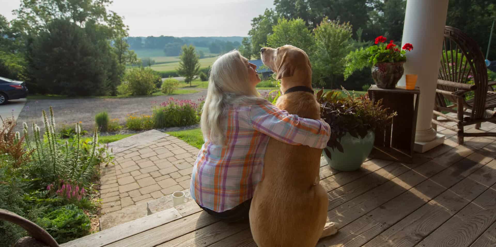 Woman sitting with a dog beside a garden